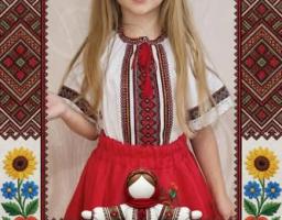 Святкова листівка із написом «"Вишивана стрічка Щастинщини"», на якій у декоративній рамці з маками та соняшниками зображена маленька дівчинка у вишиванці, червоній спідниці та віночку, а перед нею стоїть традиційна лялька-мотанка