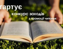 Інформаційний банер із білим текстовим оголошенням «Стартує конкурс заходів з промоції читання» зображує розгорнуту книгу на фоні зеленої трави, яку тримають руки людини