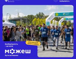 На синьому банері Міністерства молоді та спорту України з гаслом «Безбар'єрність — це коли можеш бути активним» розміщено фотографію з масового спортивного заходу, де чоловіки з протезами ніг впевнено йдуть із палицями для скандинавської ходьби під надувною аркою «Активні парки» повз глядачів, які їх підтримують