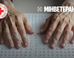 На фото зблизька зображено дві чоловічі руки, які пальцями торкаються аркуша з рельєфно-крапковим шрифтом Брайля, а у верхній частині кадру розміщено логотипи Товариства Червоного Хреста України та Мінветеранів.