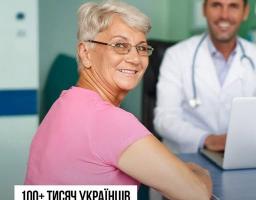На інформаційному банері Національної служби здоров'я України усміхнена літня жінка в рожевій футболці та окулярах сидить на прийомі у лікаря, який сидить на задньому плані в розмитті за ноутбуком, а внизу розміщено великий напис про те, що понад сто тисяч українців пройшли скринінг здоров'я 40+.