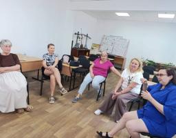 На фотографії п'ятеро жінок різного віку сидять на стільцях у колі та спілкуються в кабінеті зі світлими стінами й паркетною підлогою