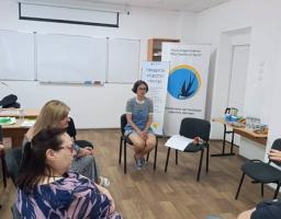 Група людей сидить на стільцях у колі під час зустрічі у світлому офісному приміщенні з білими дошками та банерами громадської організації «Десяте квітня» на задньому плані