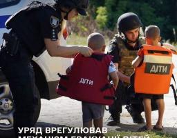 Інформаційний плакат Національної поліції та Міністерства соціальної політики України, на якому двоє правоохоронців у захисному спорядженні допомагають маленьким дітям одягнути спеціальні бронежилети з написом «ДІТИ» на тлі службового автомобіля, а знизу розміщено заголовок про те, що уряд врегулював механізм евакуації дітей із зон бойових дій без супроводу батьків.