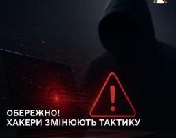 На зображенні у темних тонах силует людини в капюшоні сидить перед ноутбуком із червоним знаком оклику в трикутнику на екрані, а знизу розміщено попереджувальний напис «ОБЕРЕЖНО! ХАКЕРИ ЗМІНЮЮТЬ ТАКТИКУ».